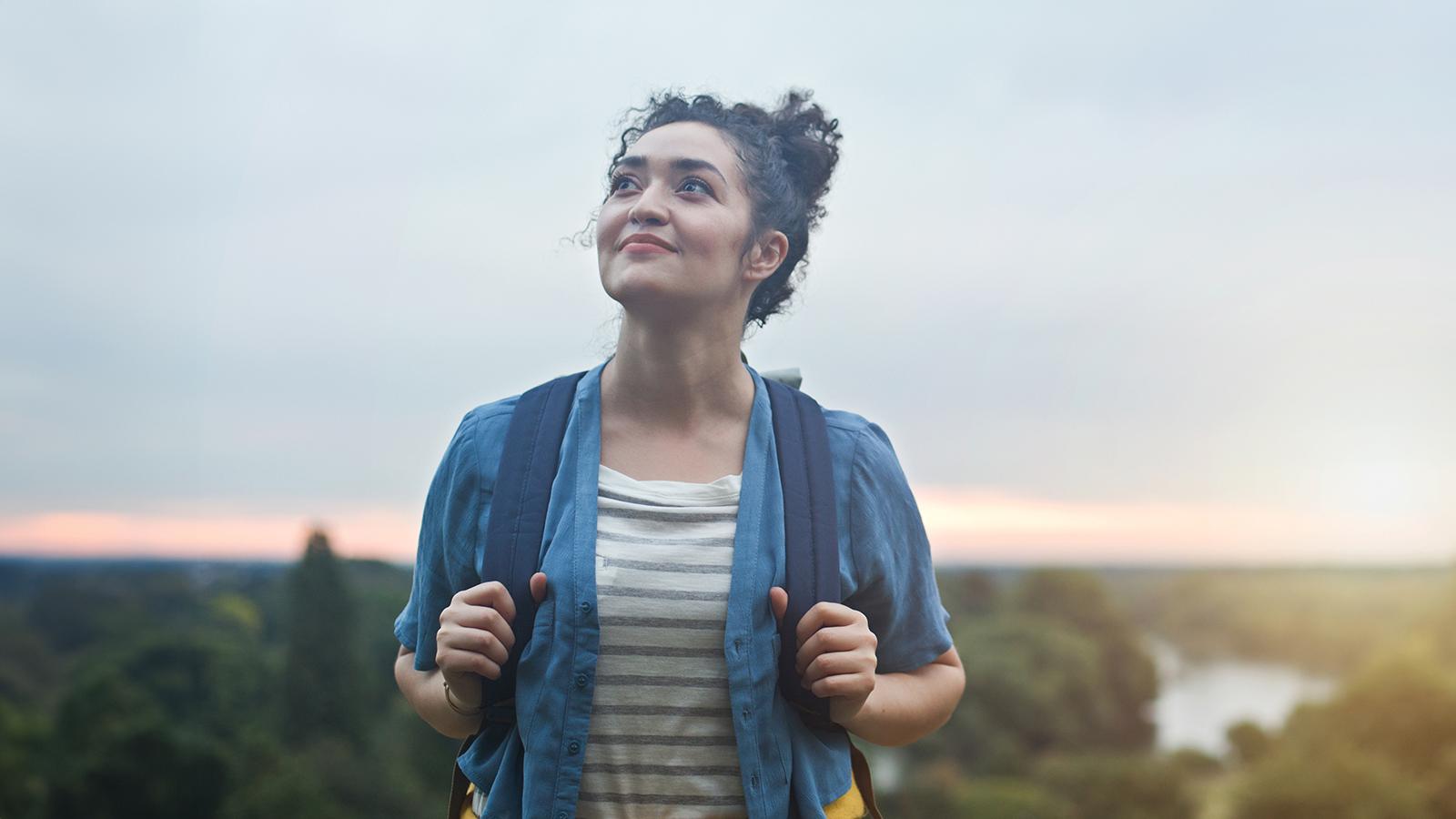 Woman smiling holding her backpack straps