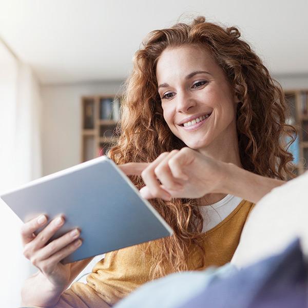 Woman on her couch using her tablet.