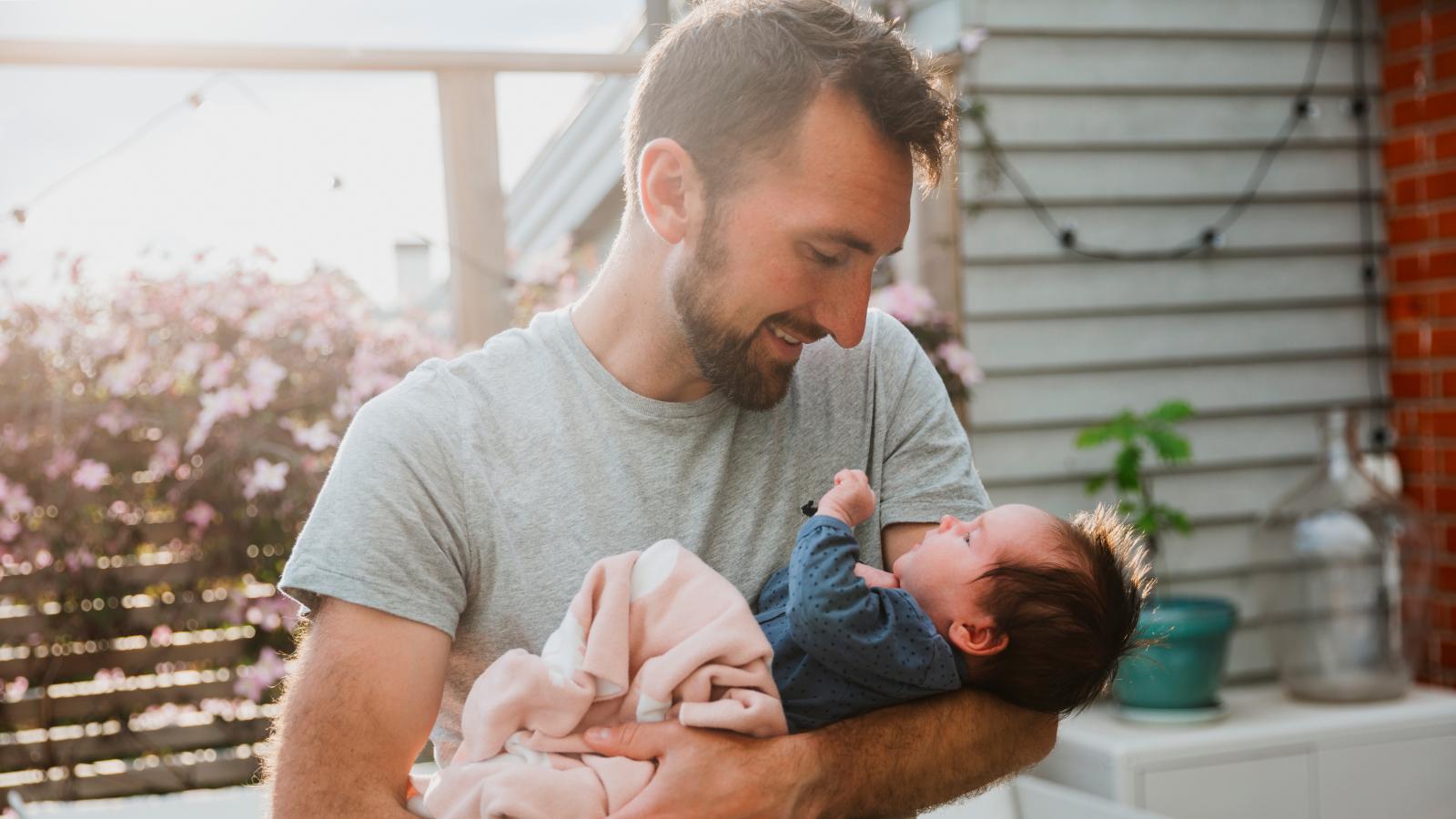 A man holding his newborn baby at home.