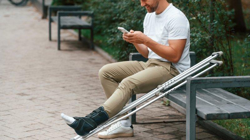 Man seated with crutches man seated with crutches