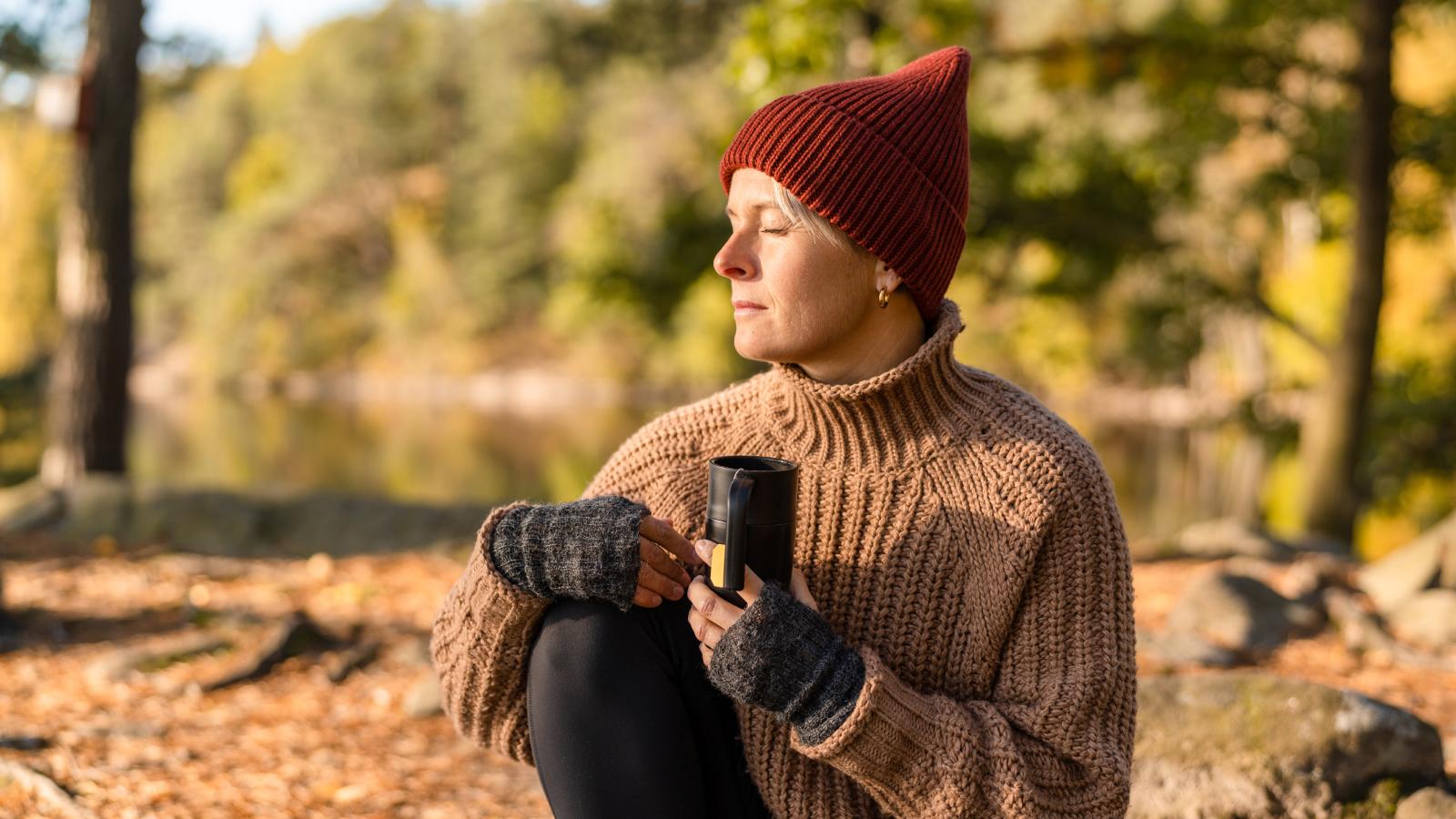 Woman sitting in a forest and drinking tea