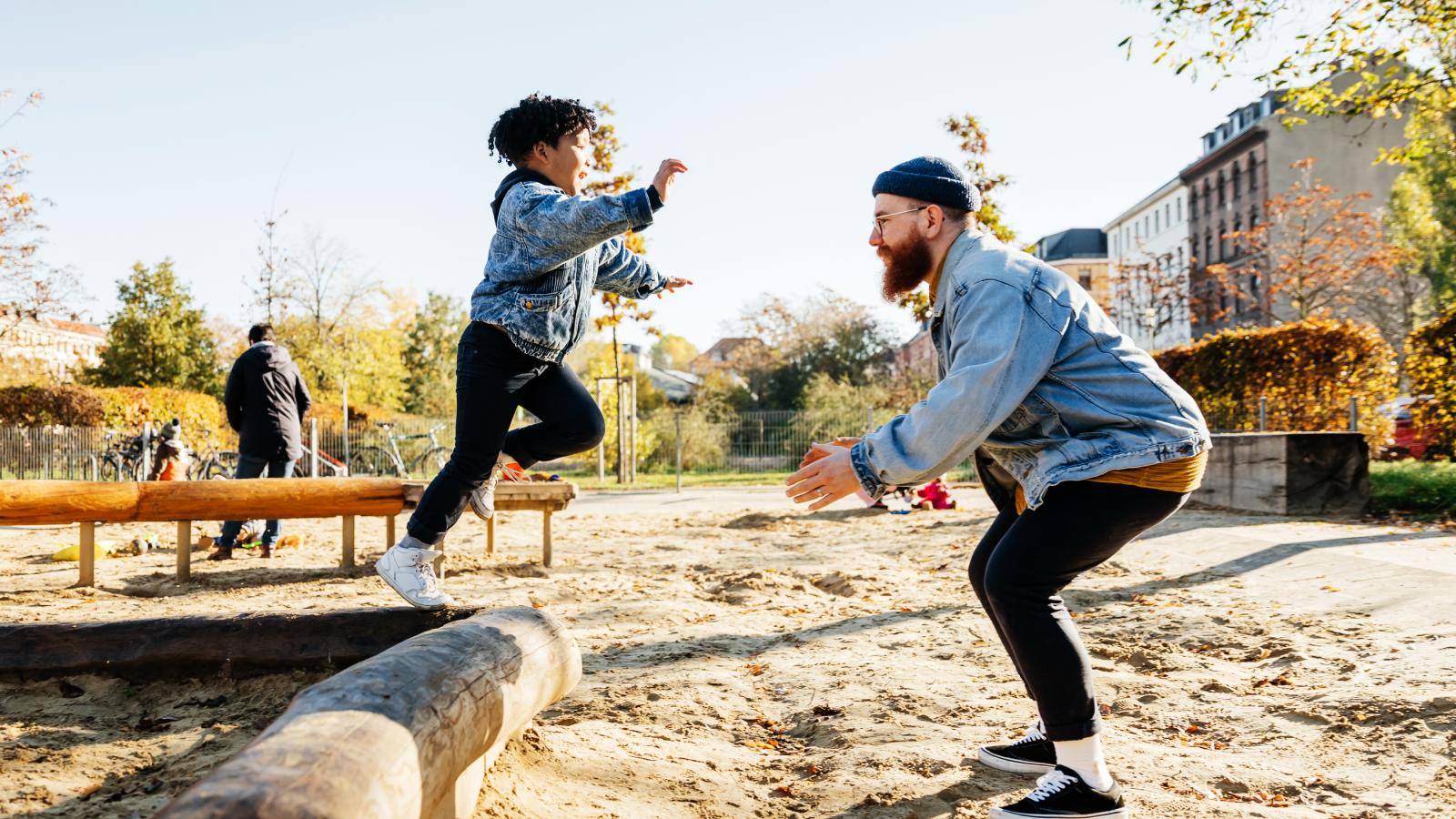 Young boy leaping into his father's arms at the playground. Young boy leaping into his father's arms at the playground.