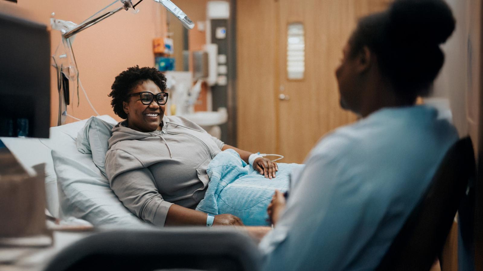 Woman in hospital bed speaking with a registered nurse. Woman in hospital bed speaking with a registered nurse.