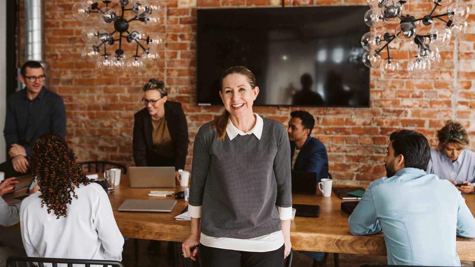 Happy businesswoman standing and colleagues discussing