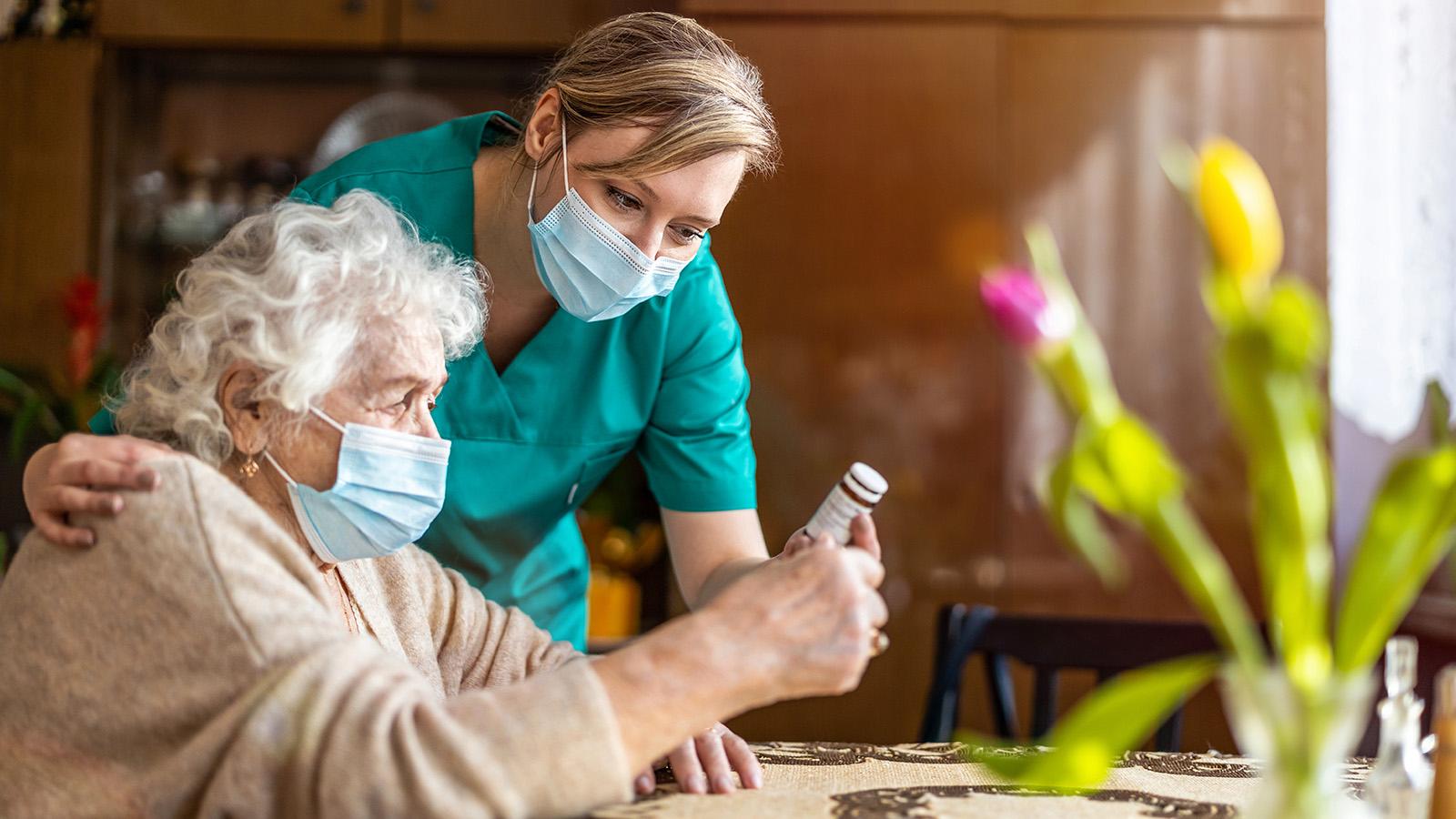 Home caregiver helping senior woman with medication