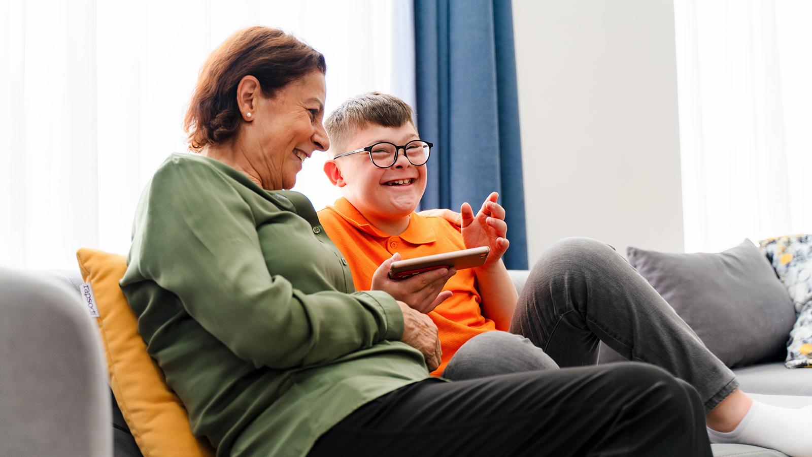 Woman laughing on the couch with a boy with down syndrome