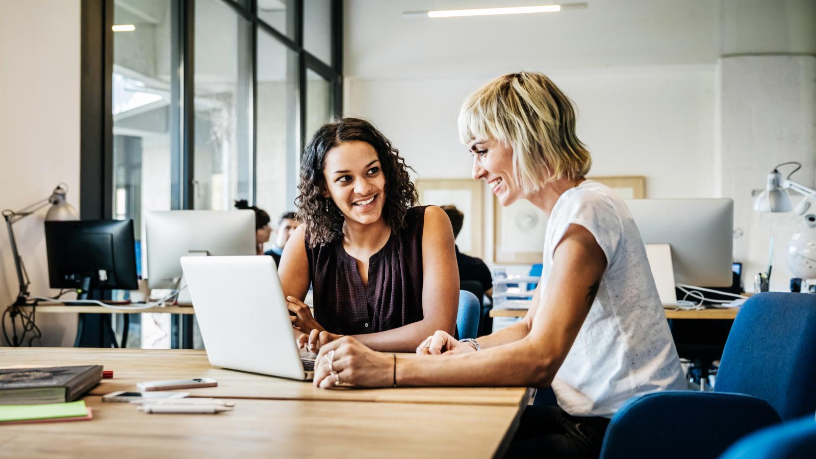 Two businesswomen talking in a meeting with laptop