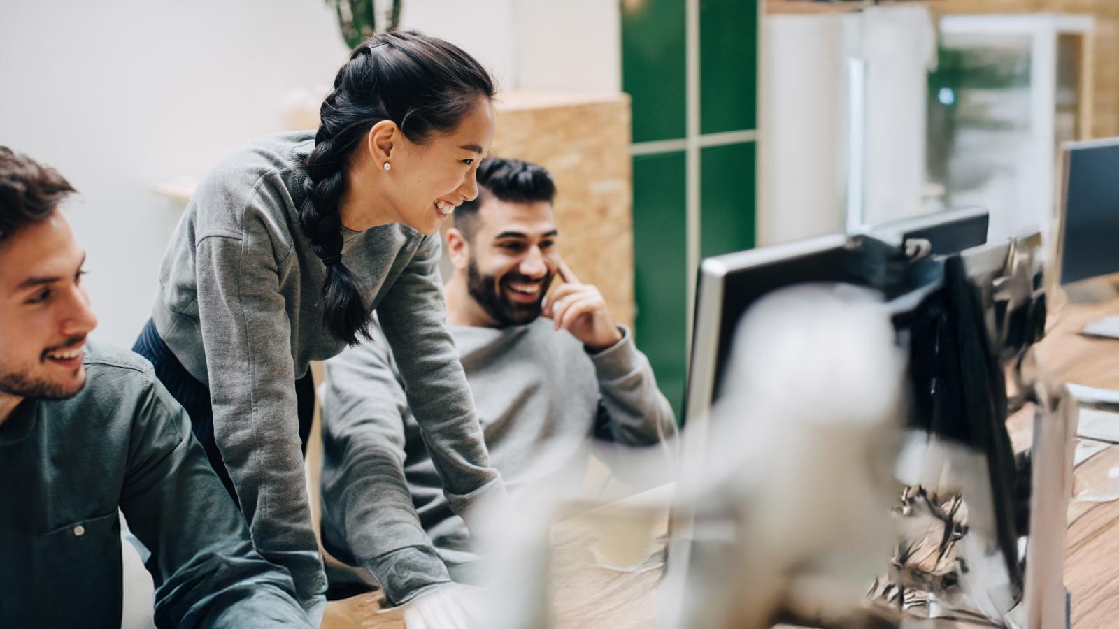 group-of-people-in-office-looking-at-computer-smiling group of people in office looking at computer smiling