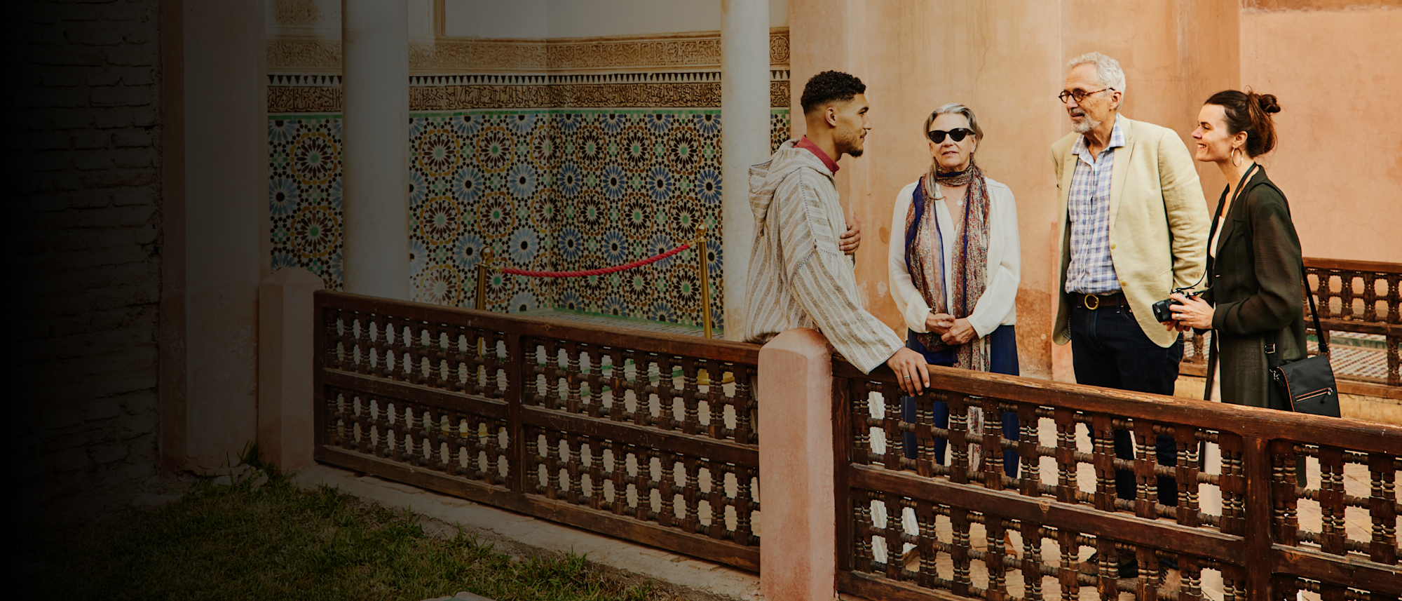 Wide shot of inquisitive senior couple and adult daughter happily engaging with tour guide at historical site in Marrakech