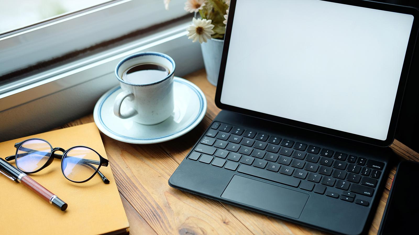 Laptop next to a coffee cup on a desk