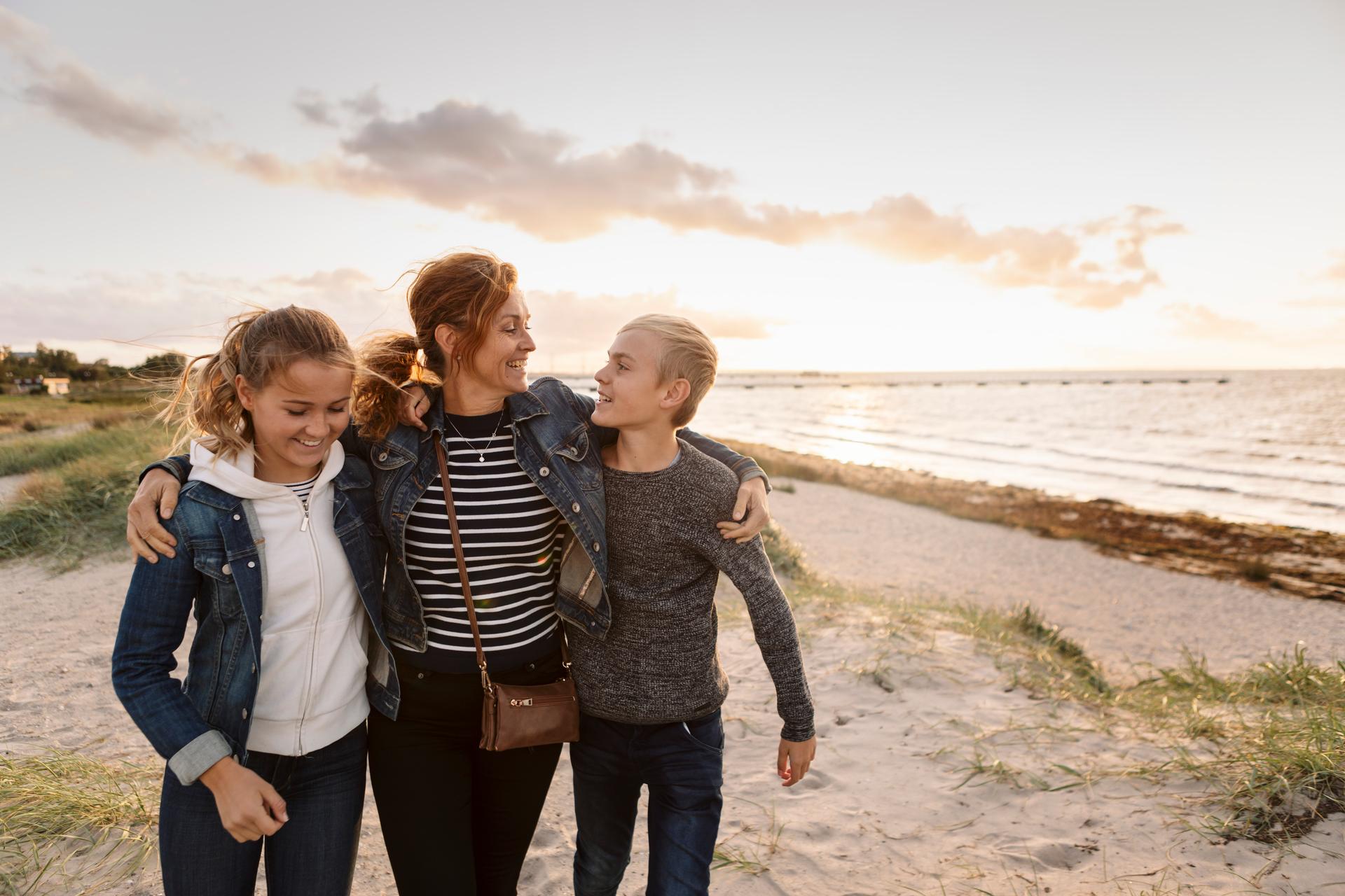 A mother and her daughters walking on the beach.