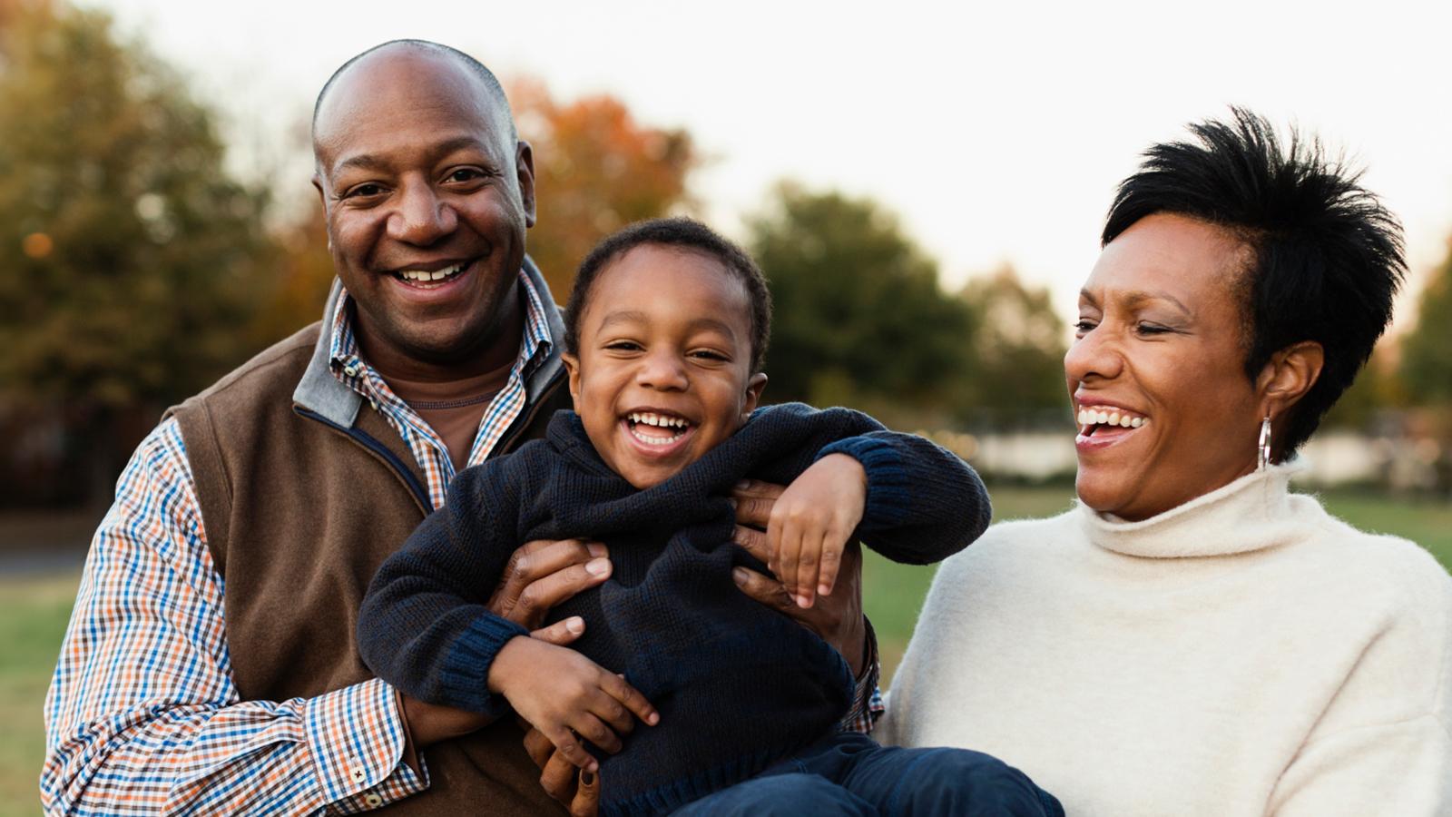 Retired grandparents holding their grandson and laughing