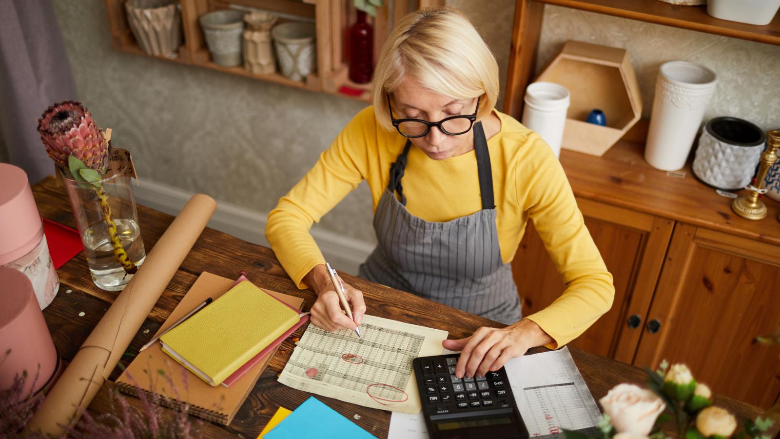 Female businesswoman counting finances using calculator