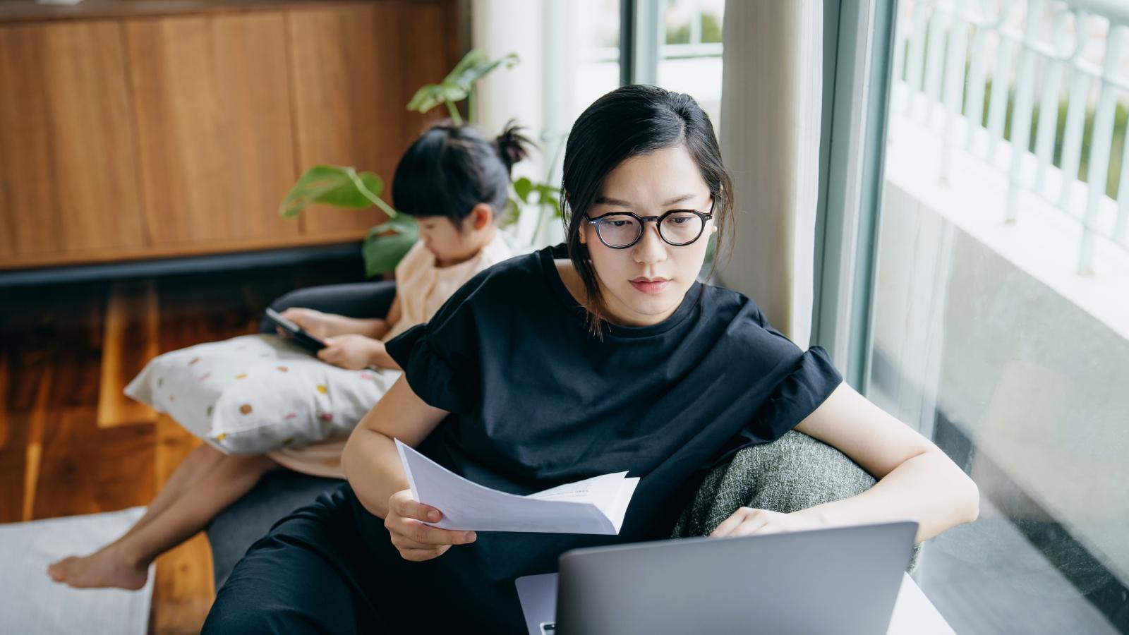 Mother doing calculation on laptop