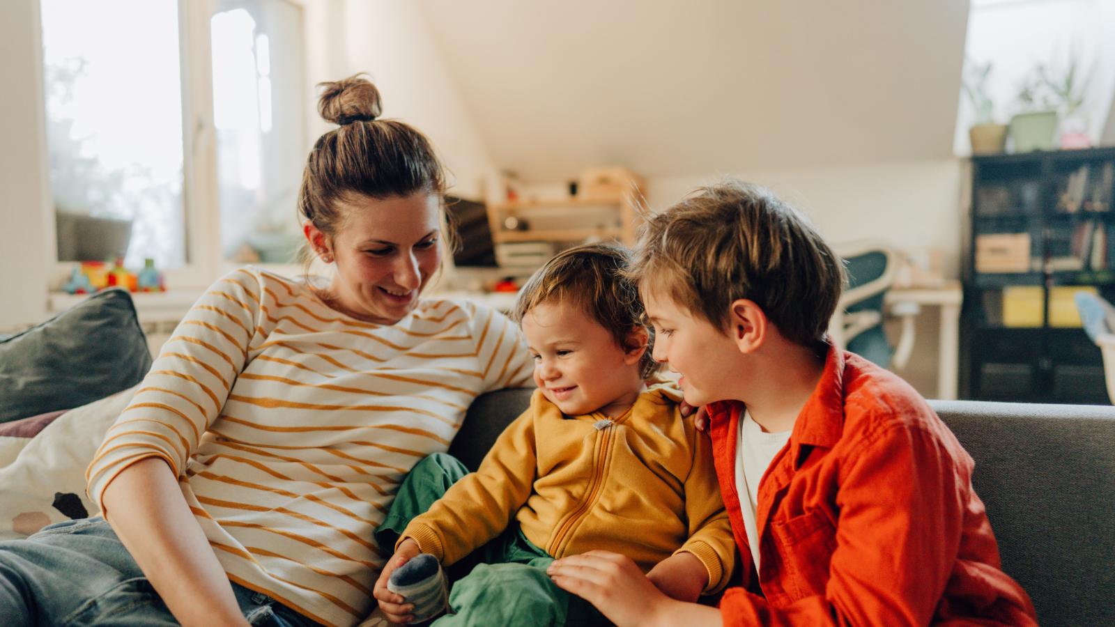 Happy mother and her kids on a couch at home