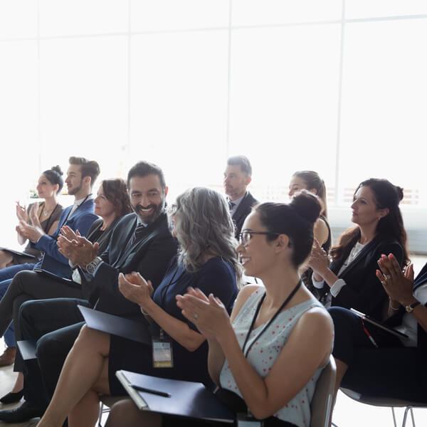 Group of employees sitting in a chair and applauding.