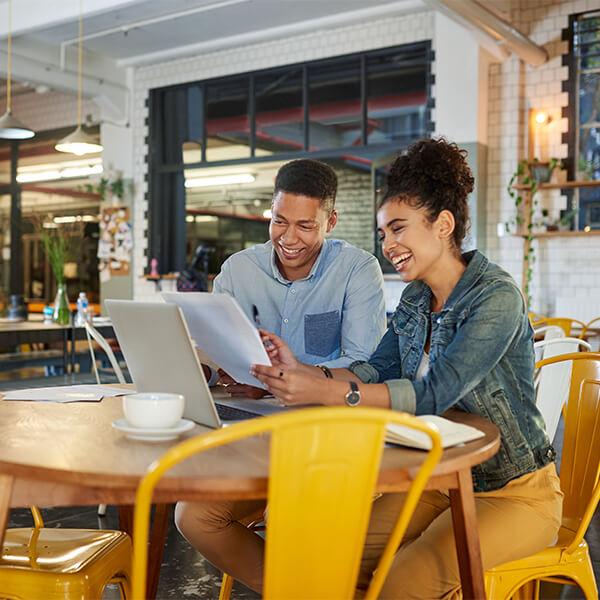 Two employees laughing at work in front of a laptop