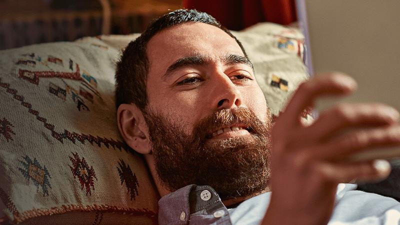 Man laying down on his bed watching his tablet