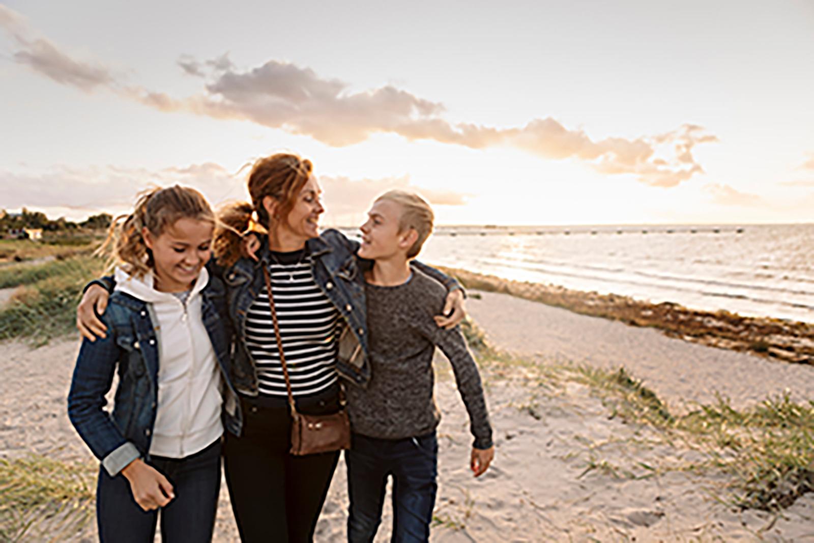 Mother and her two preteen children walking on the beach. Mother and her two preteen children walking on the beach.