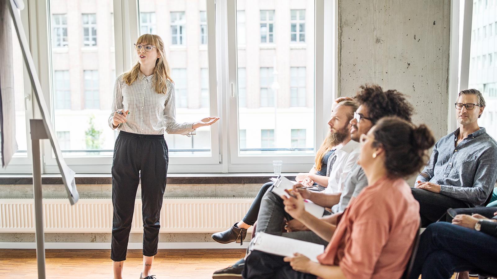 Woman presenting to her coworkers at a meeting
