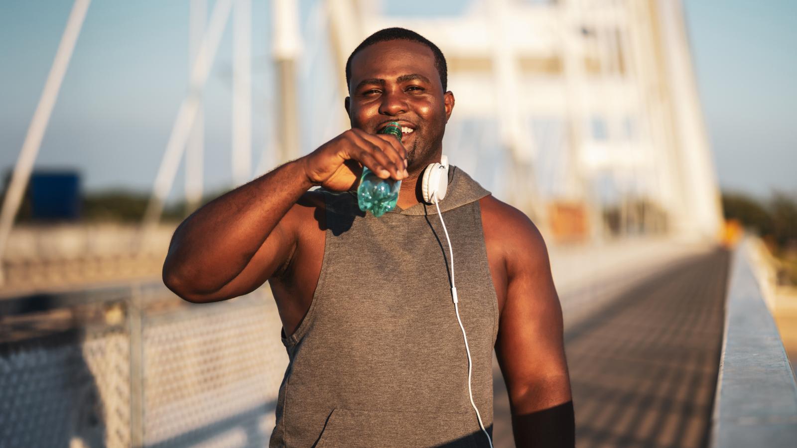 Young African American man drinking water after exercise.