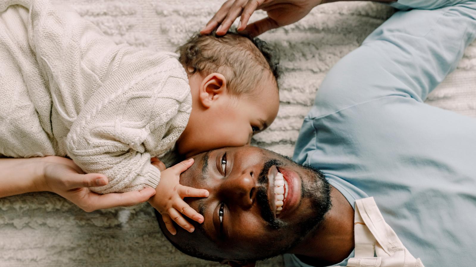 Father laying on the floor and playing with baby.