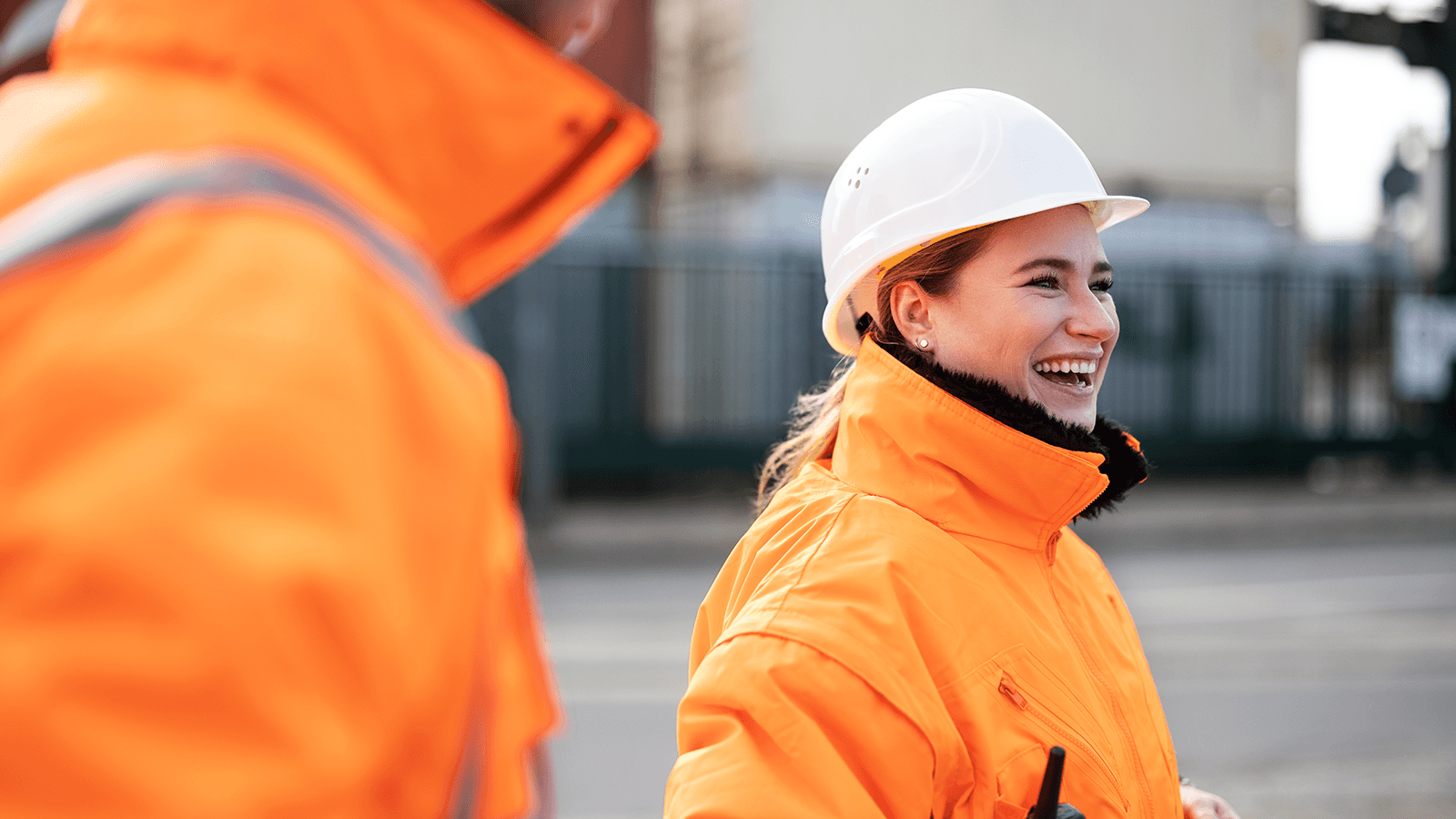 Dental benefits to build upon Woman in bright orange jacket wearing a construction hat smiling