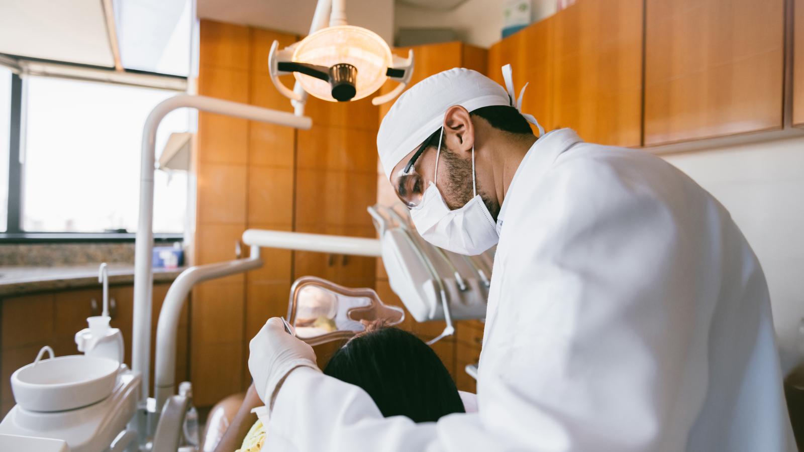 Young orthodontist examining a young woman's teeth