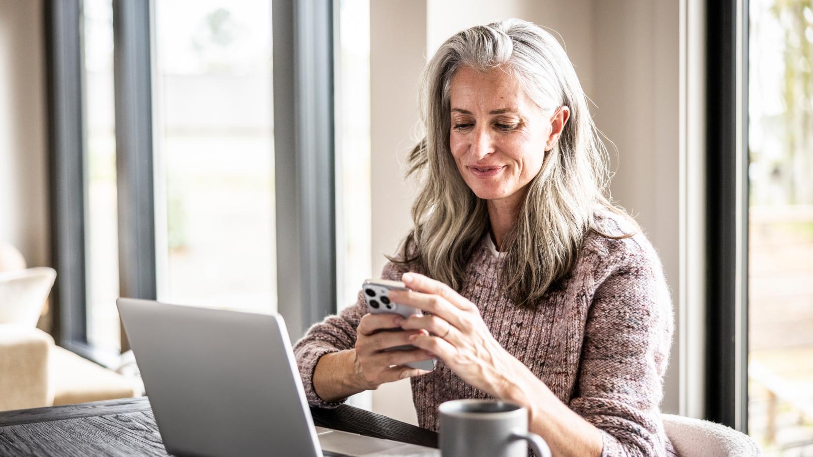 Senior woman using smartphone and laptop Senior woman using smartphone and laptop