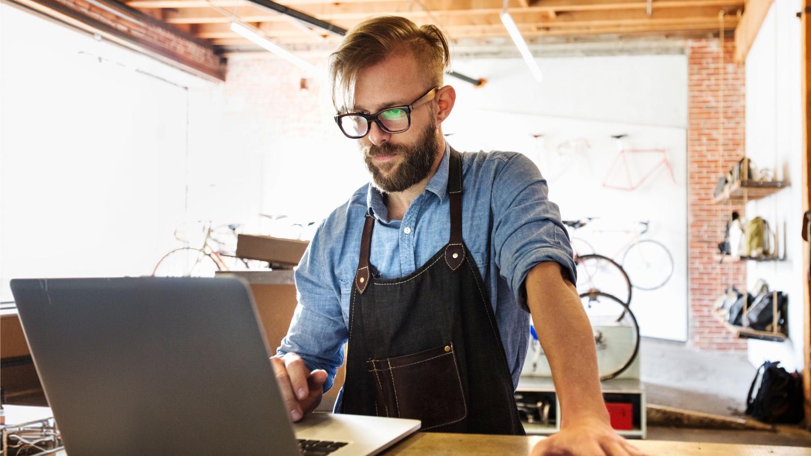Man in a bike shop doing admin work on a computer.
