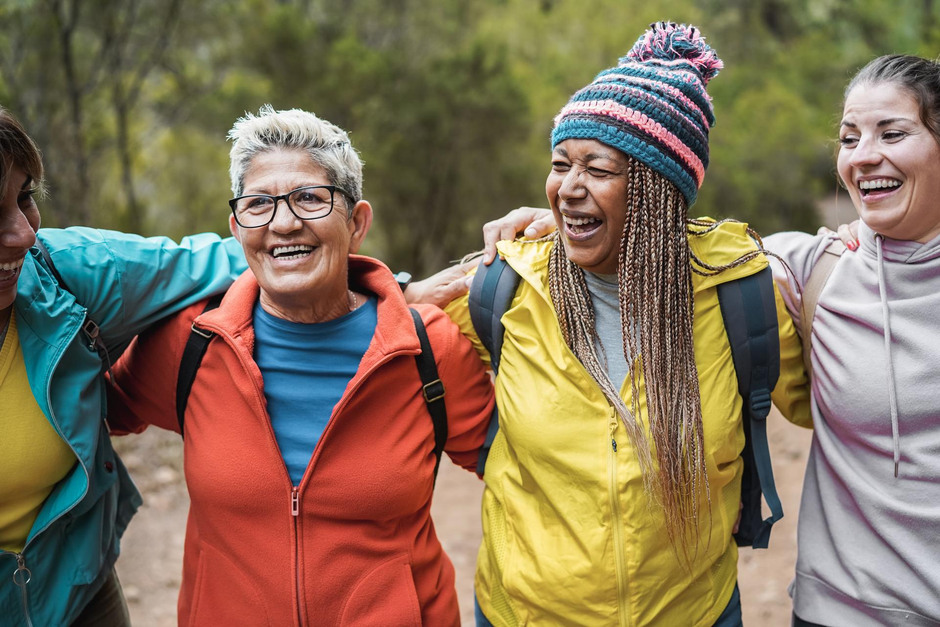 Women with arms around one another having fun during trekking day in to the wood