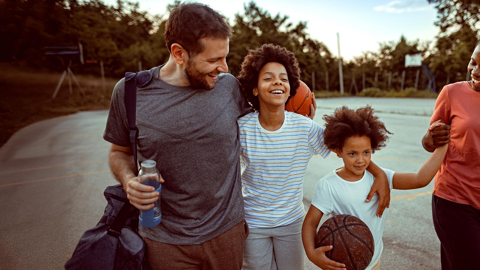 Man walking with 2 boys holding a basketball