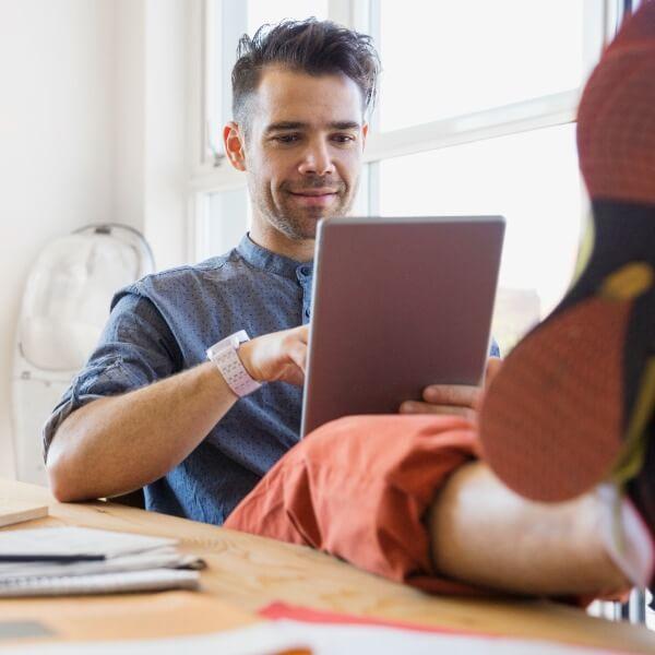 A man leisurely reading from a tab.