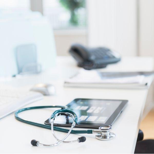 A stethoscope next to a tab and a telephone.