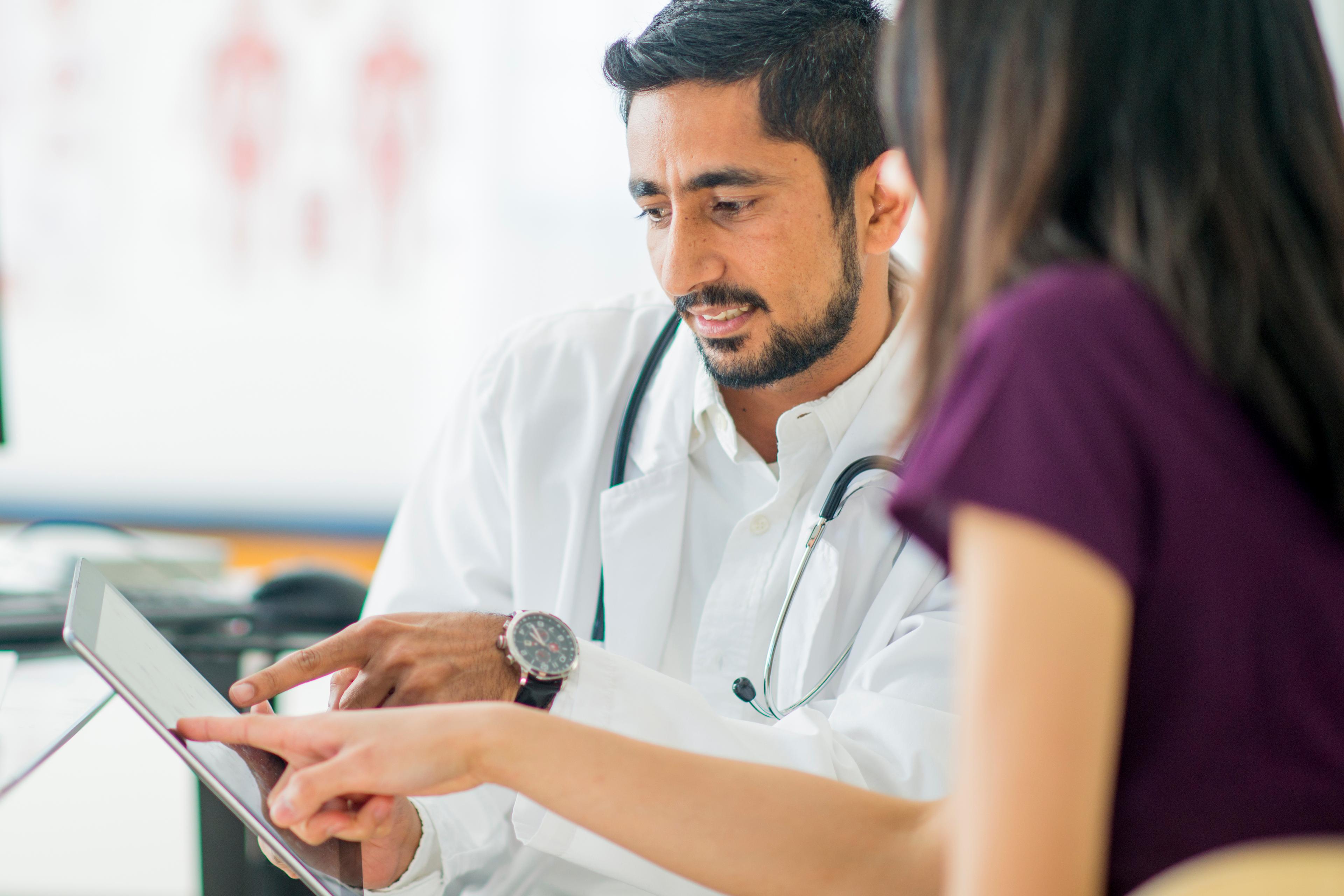 Physician and woman look at tablet