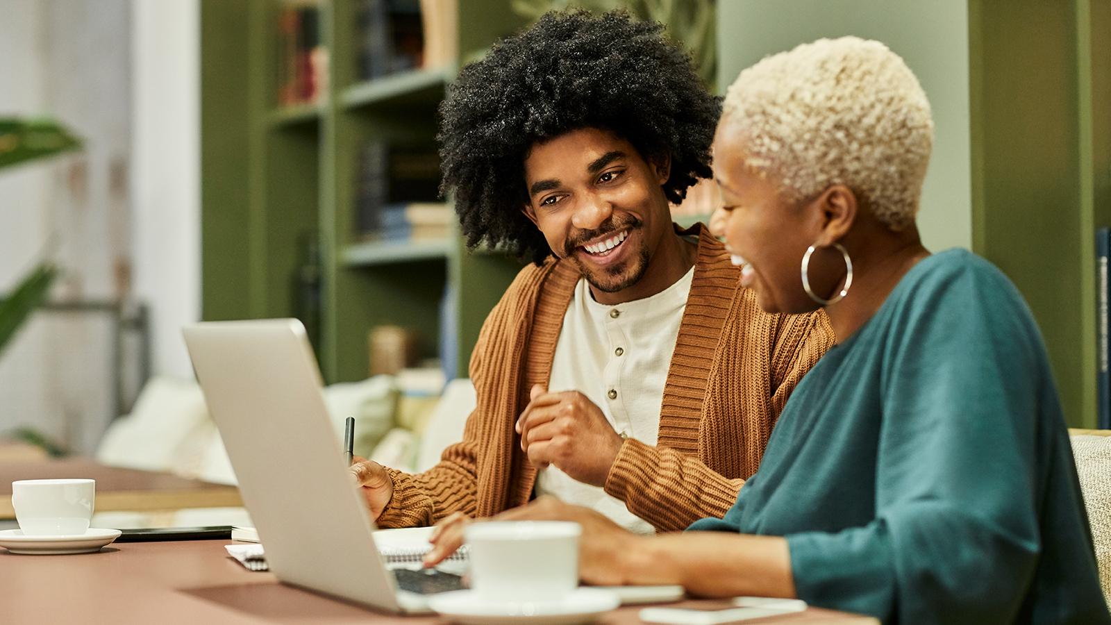 Two co-workers looking at a laptop at work Two co-workers looking at a laptop at work