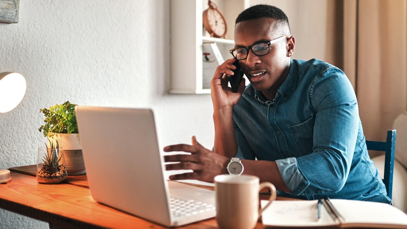 Man talking on phone while using laptop