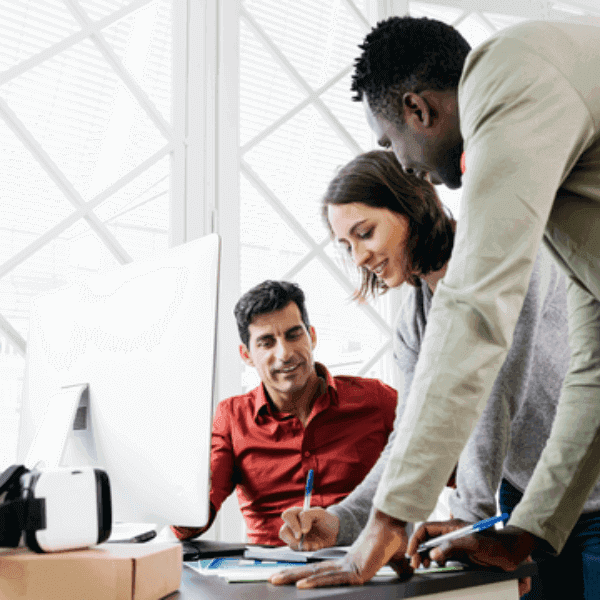 Three employees in a discussion looking at a paper.