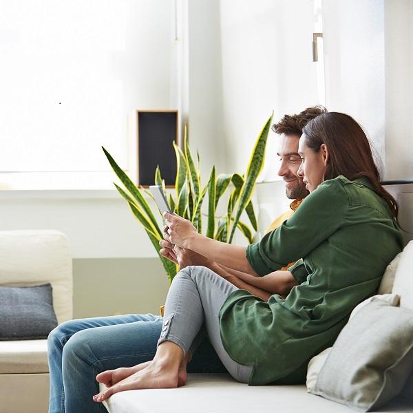 Couple on a couch looking at a tablet.