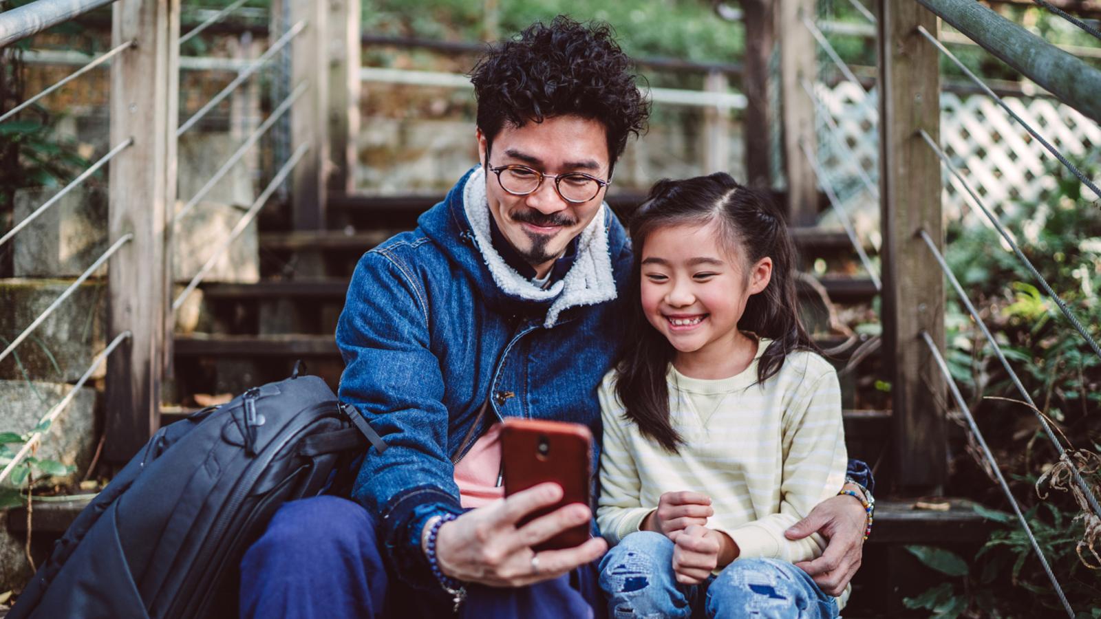 Father and daughter smiling while taking a selfie photo