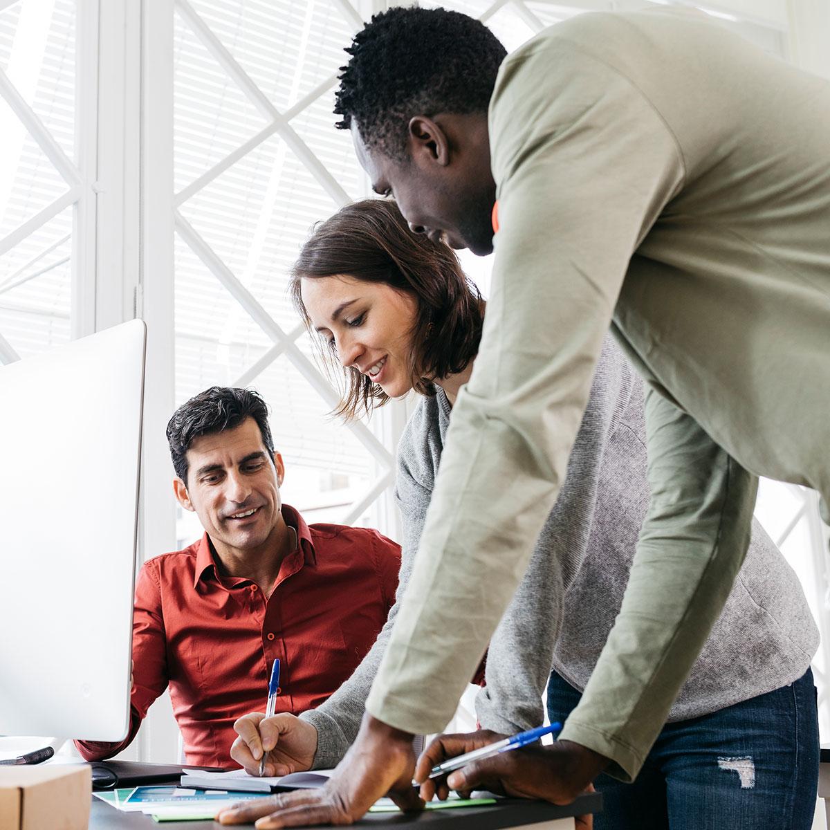 Two men and one woman discussing in office.