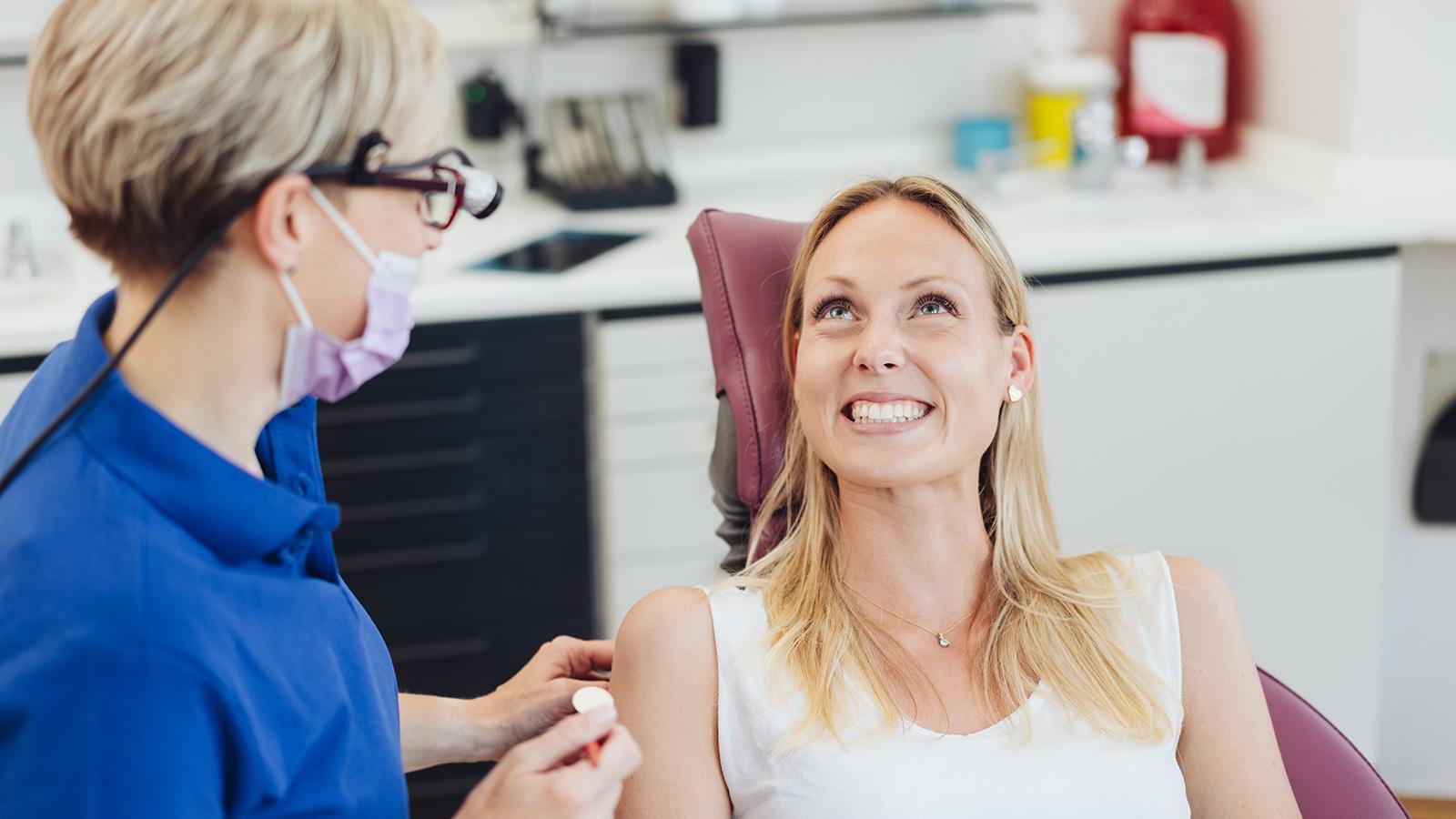 Smiling patient with her dentist sitting in her procedure room