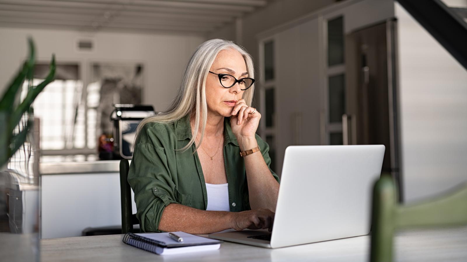 Focused senior woman at home using laptop
