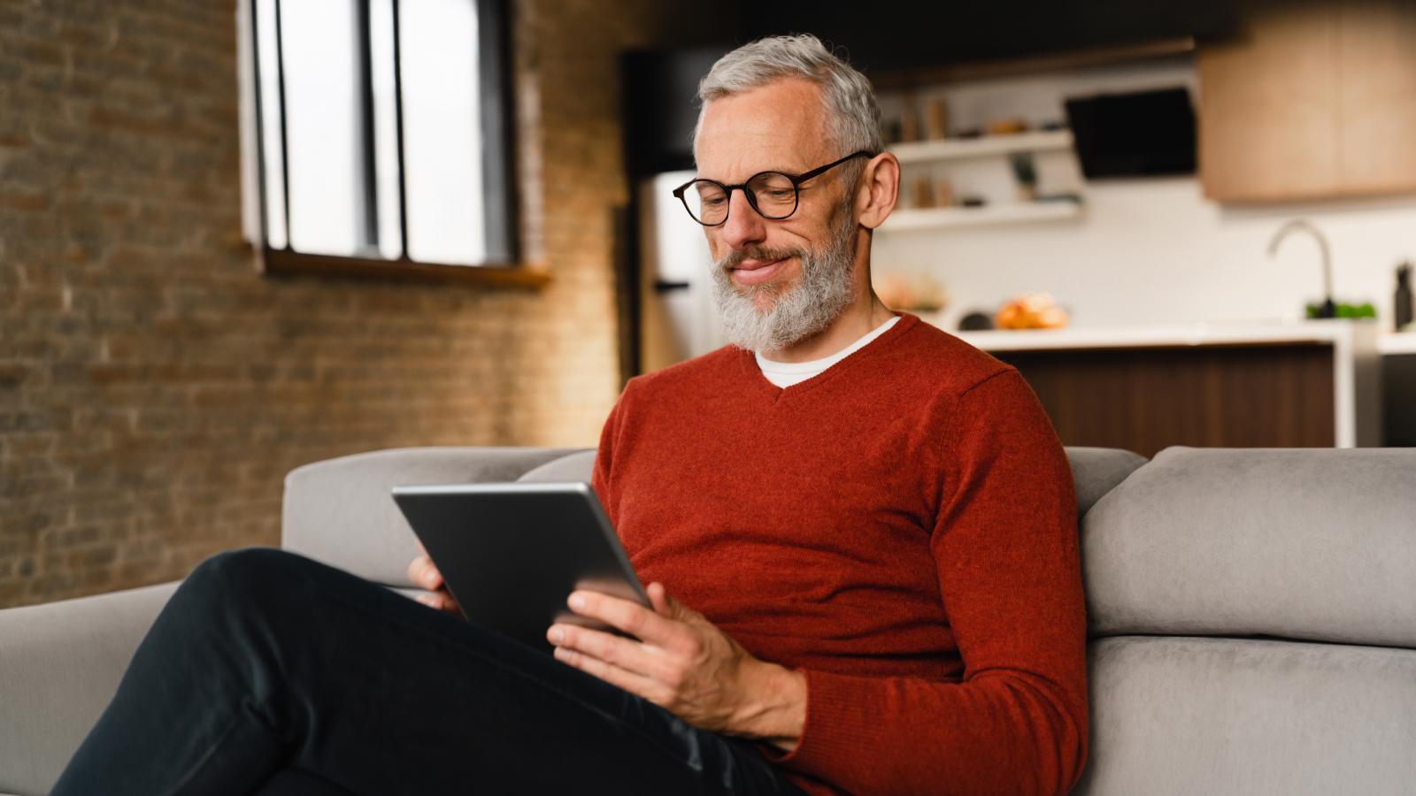 Man with glasses viewing a tablet.