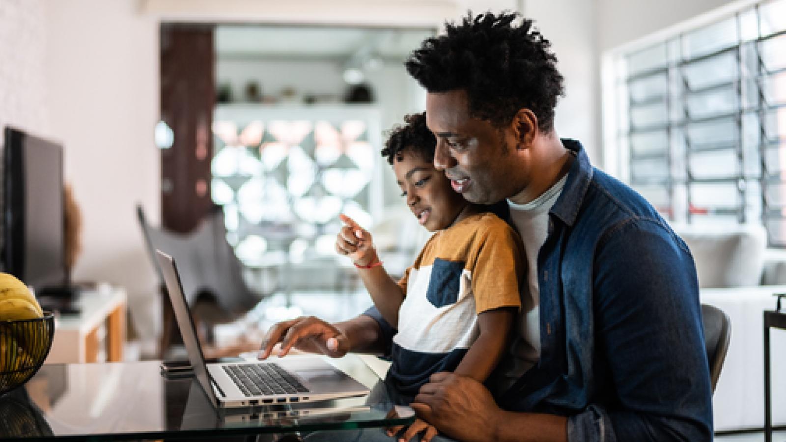 Father and son using laptop at home.