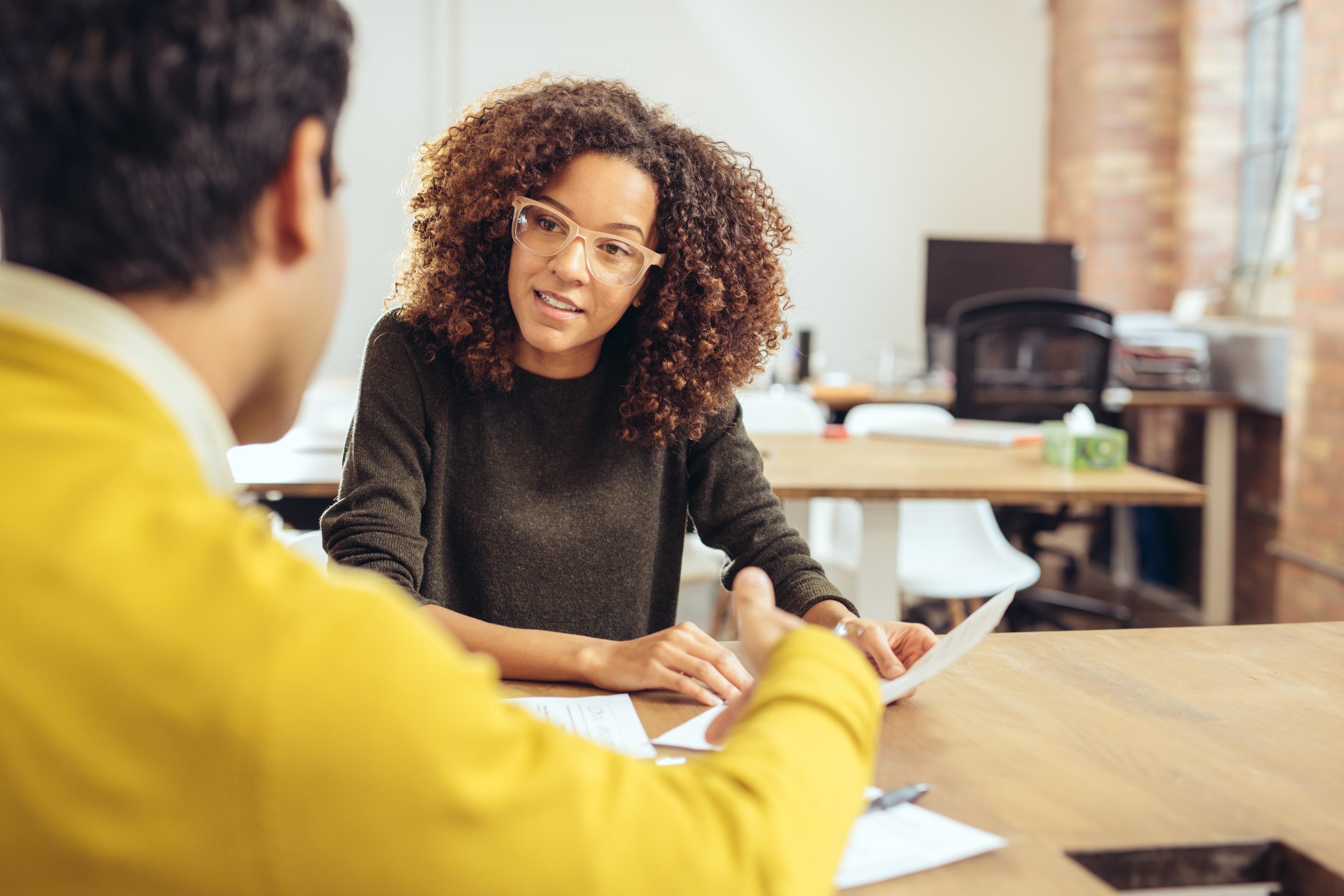Woman talking with a colleague about a written communication.