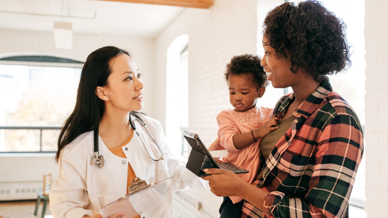 Woman holding her child and speaking with her physician. Woman holding her child and speaking with her physician.