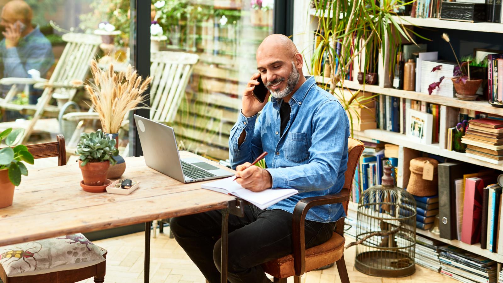 Man working on laptop and taking notes.