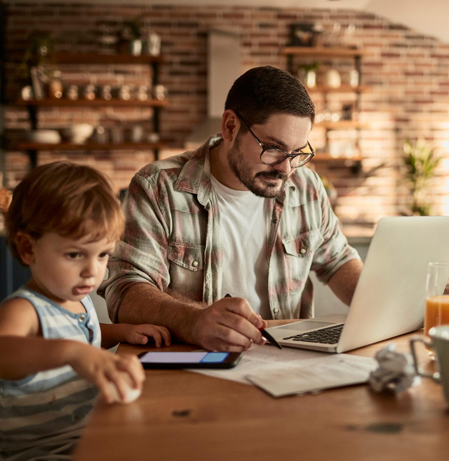 Father working on his laptop with his infant son