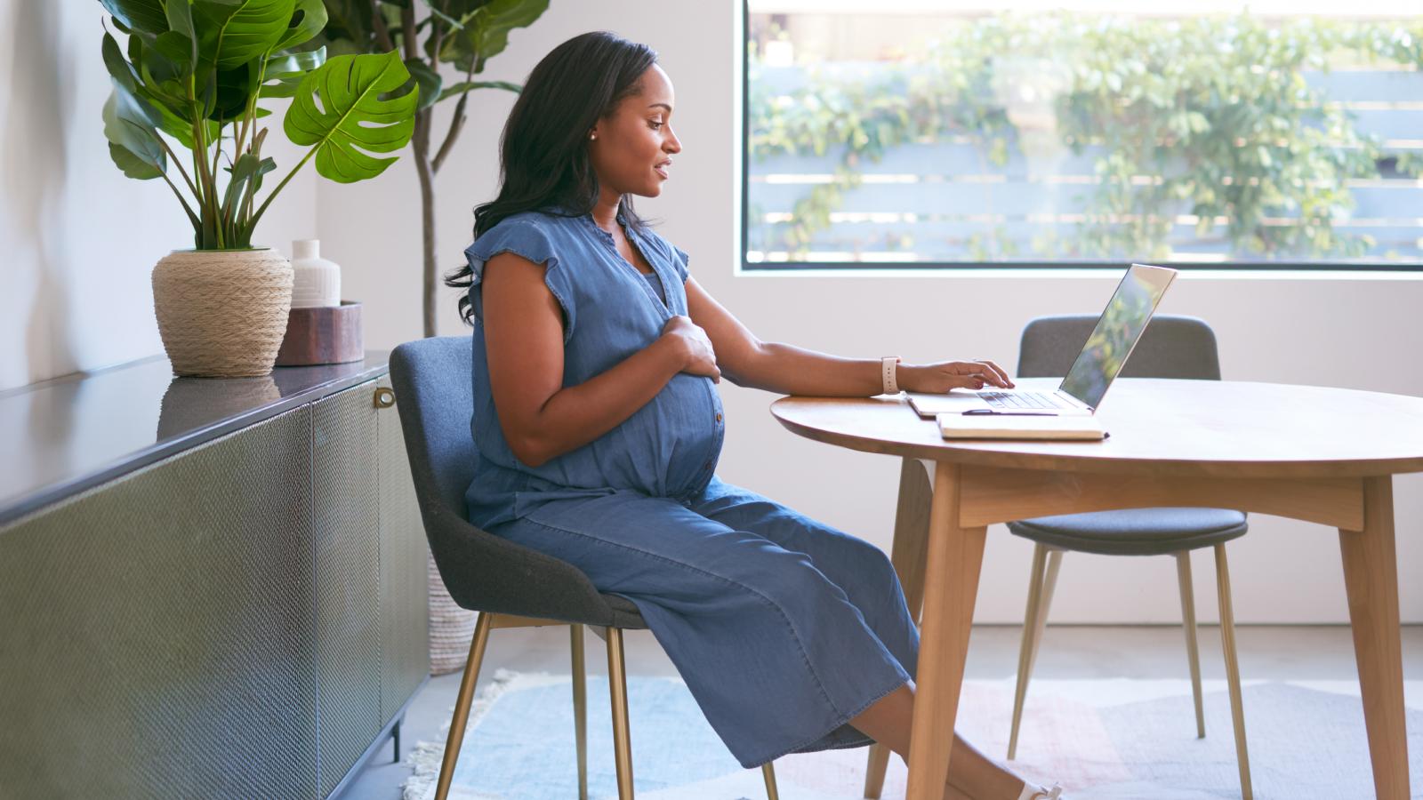 Pregnant woman using laptop at home